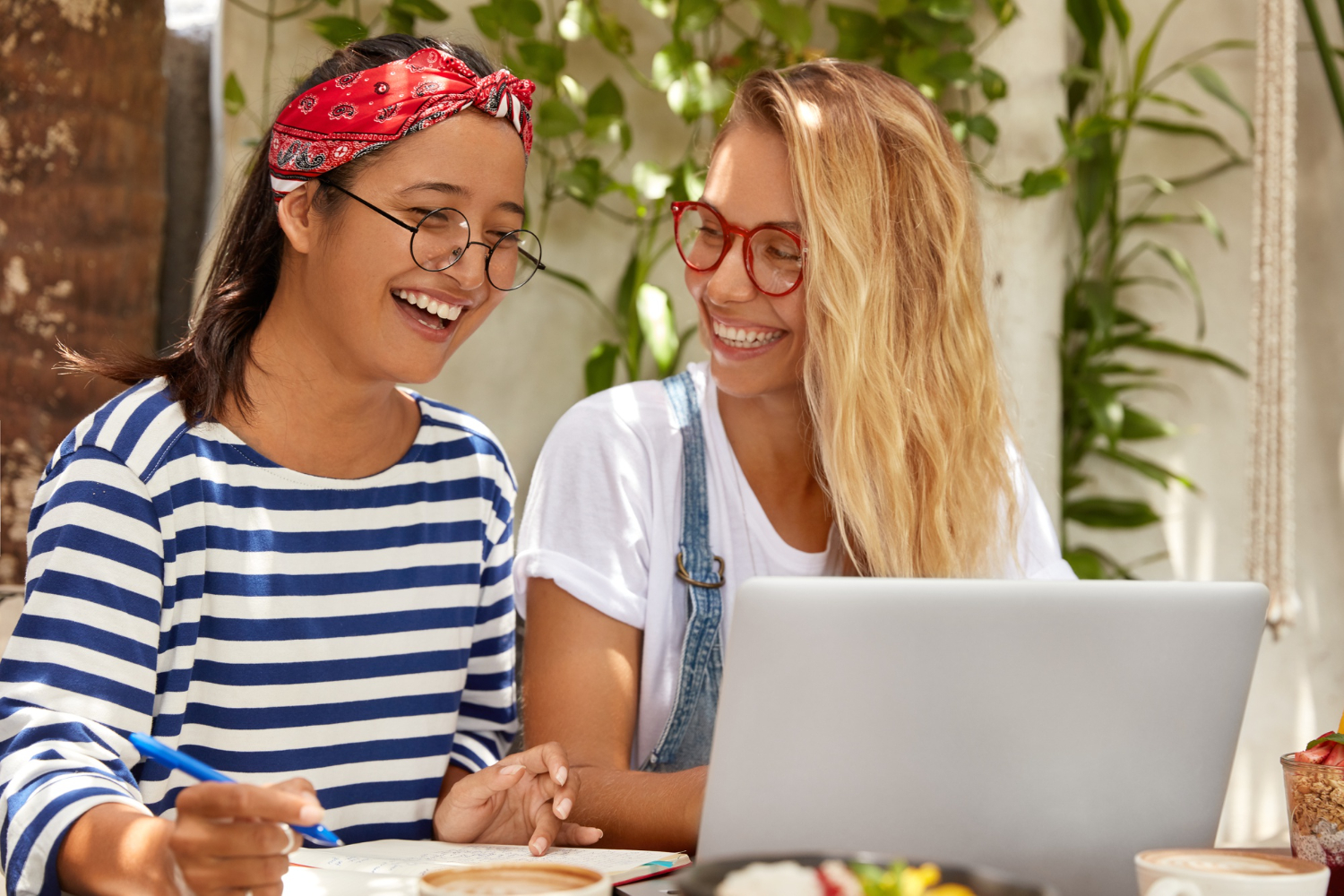 Two women are looking into laptop and smiling