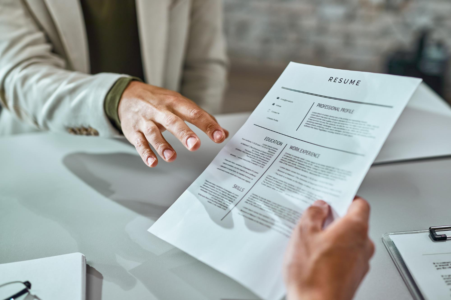 Close-up of a person handing over a resume during a job interview at a desk